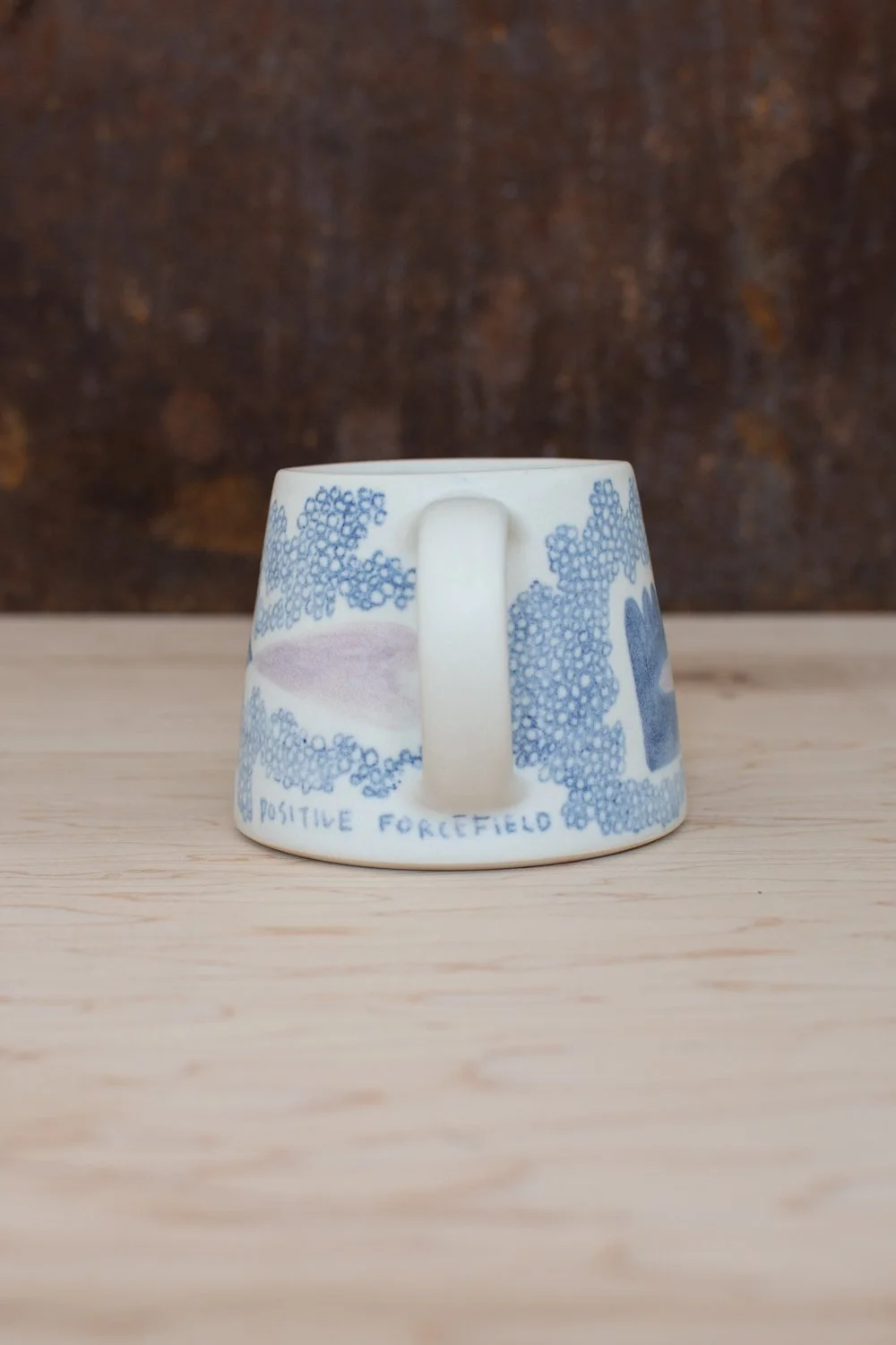 Eleanor Annand — Hand-thrown porcelain mug with blue illustrations painted on the surface.