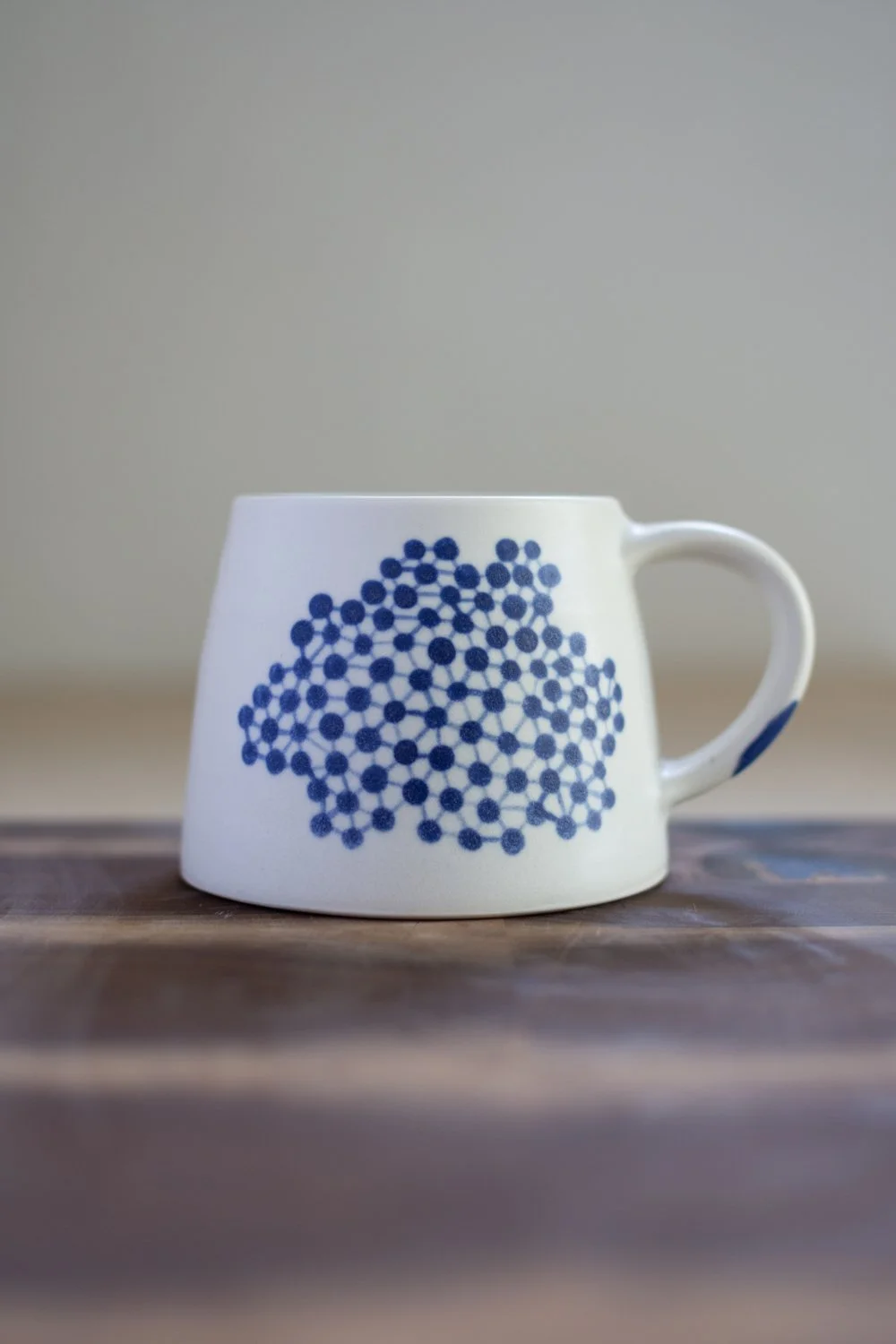 Hand-thrown porcelain mug with blue illustrations painted on the surface.