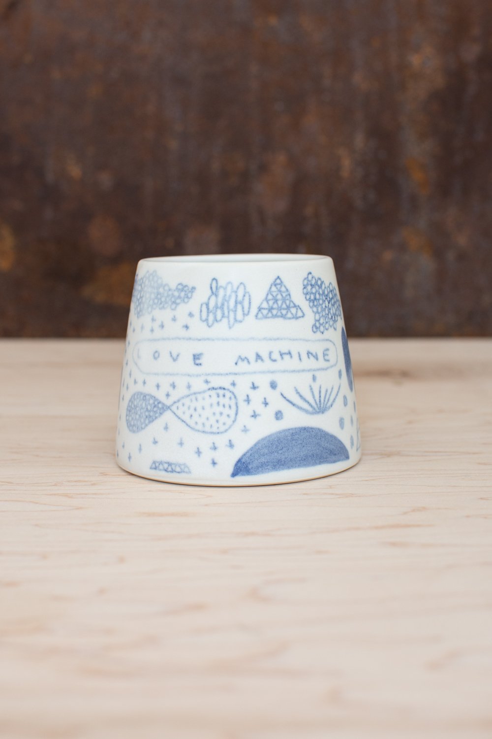 Hand-thrown porcelain mug with blue and pink illustrations.