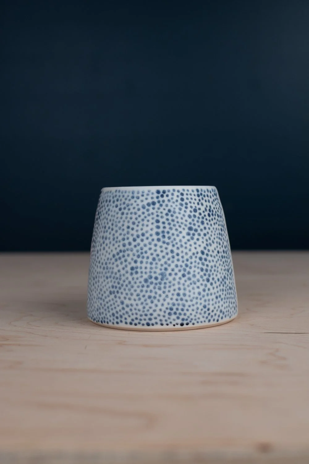 Hand-thrown porcelain mug with black illustrations painted on the surface.