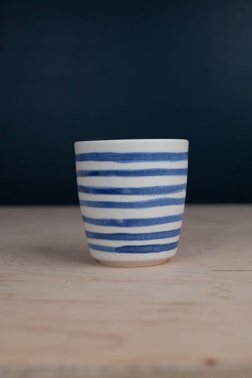 Hand-painted cup with blue underglaze over creamy white porcelain.