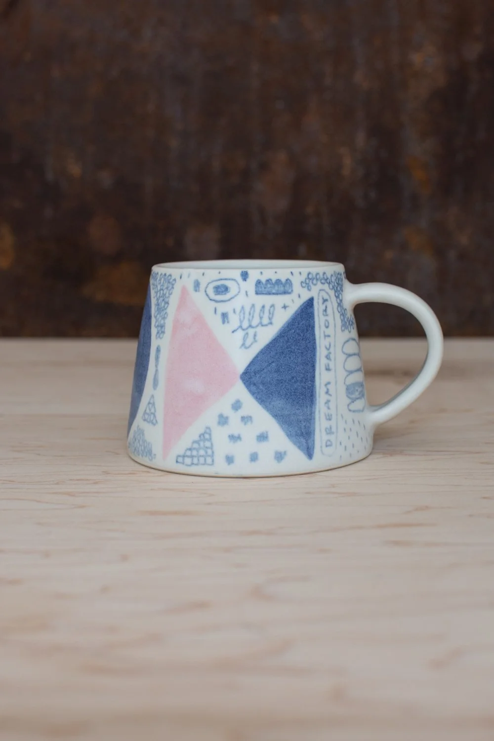 Hand-thrown porcelain mug with blue illustrations painted on the surface.
