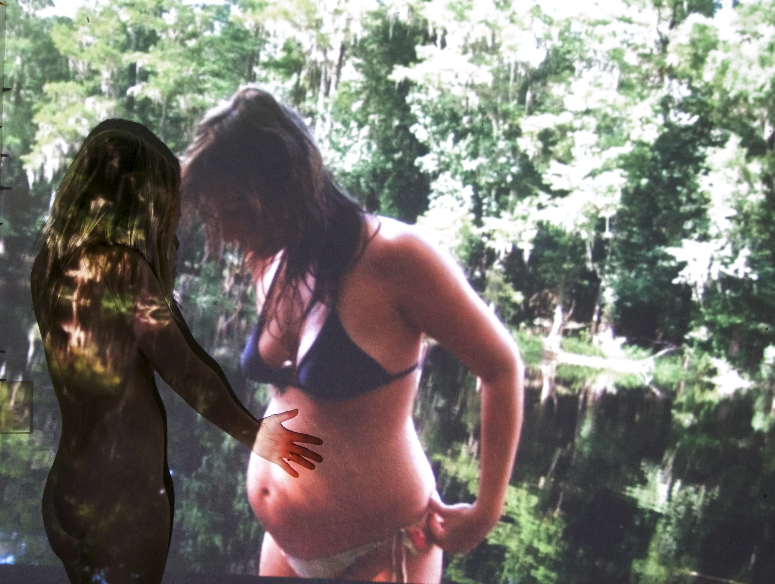 I projected old photographs on the wall and rephotographed them with my current self in the memory. Reunited with my 23 year old pregnant self. I tell her: Girl, You have no idea what you're doing. In a month from now you'll see your blood on the walls of the hospital you fought going to, and the freshest most familiar beautiful baby face on your chest. You won't have sex for 4 months because it hurts so bad. The first time you see him smile, it's a feeling that makes you want to jump and laugh and bawl all at the same time. That baby will suck on your tits for 3 years. You won't sleep. You'll leave your family in Florida and move to California, and you won't stop missing them. Your relationship with his dad falls apart because among other things, now your son is your tiny boyfriend. You'll drink a lot of whiskey and put on the cartoons you said you'd never let him watch. Your concept of self will disintegrate and be put back together in a way you never envisioned. Then all of a sudden, he's finished a year of kindergarten. You pay your own bills. You finally have a washer and dryer in your house and a sweet, empathetic, creative 6 year old human that you snuggle almost every night. And sometimes you yell at him but mostly you're in awe. Yeah, you get lonely, but it's sure as hell better than feeling trapped. And somehow, this whole time you've kept making art. You'll stop drinking when you're stressed out and do your goddamned human homework because nope, life is NOT fair, but there are tools to make it easier, and you both deserve that. Tonight, you'll stare at him while he's sleeping and try to unravel the mystery of how you're even here in this bed, and what it is exactly that's made it all worth it.