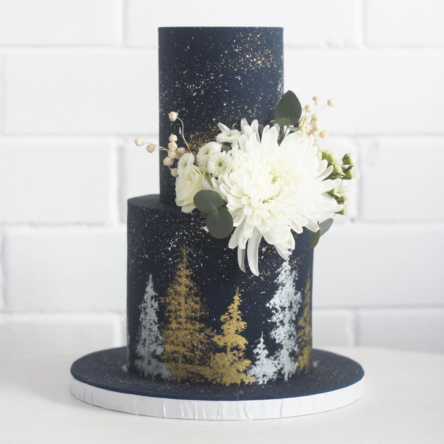 A starry night sky themed wedding cake! A gold and silver splatter on the entirety of the cake and hand painted tree line. I used the Bob Ross &lsquo;happy tree&rsquo; method to achieve the ever greens. Can confirm, works a charm! #wedding #weddingcake #happytrees