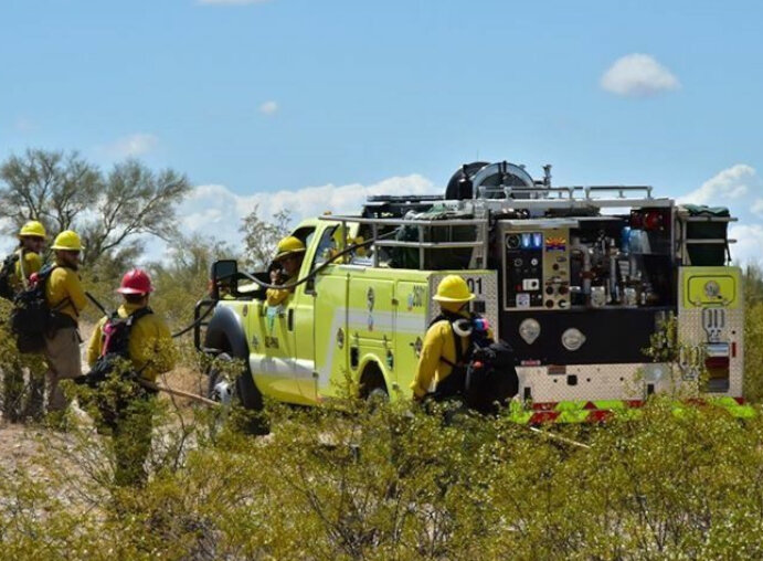 side-back-view-of-yellow-brush-truck-in-field-with-firemen-720x480.jpg