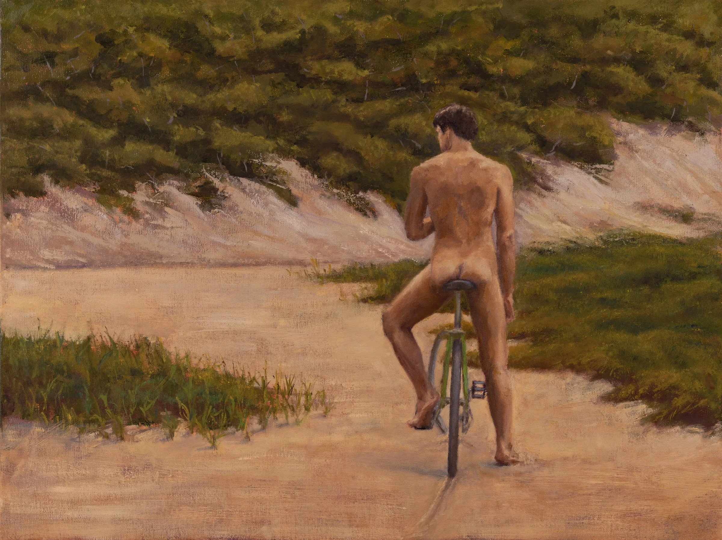 A nude cyclist pauses on a sandy dune path, suspended between motion and rest. Seen from behind, he inhabits the landscape with quiet ease.
