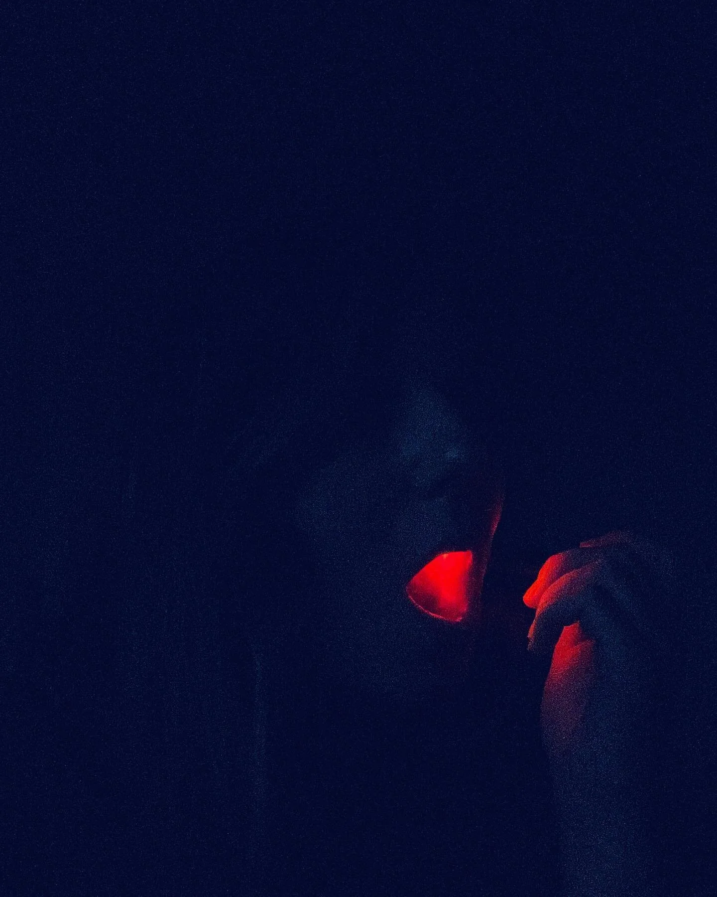 self portrait with flashlight, 2023 
ID: a dark self portrait in dusky blue light my mouth open and illuminated red by the light of a flashlight seen through the flesh of the side of my cheek