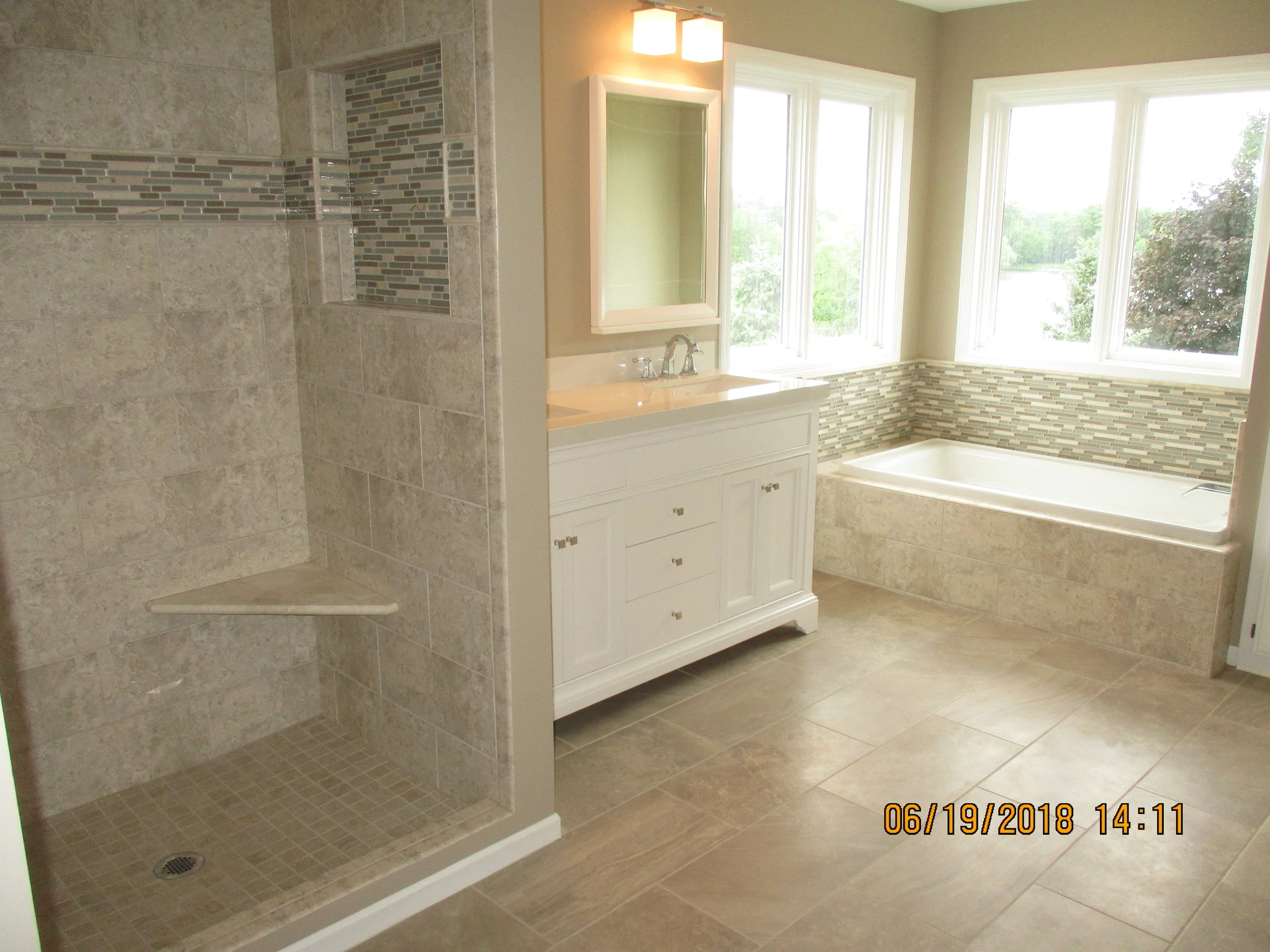 New custom shower pan, solid corner seat, new tub with tile, vanity and new floor tile and wall