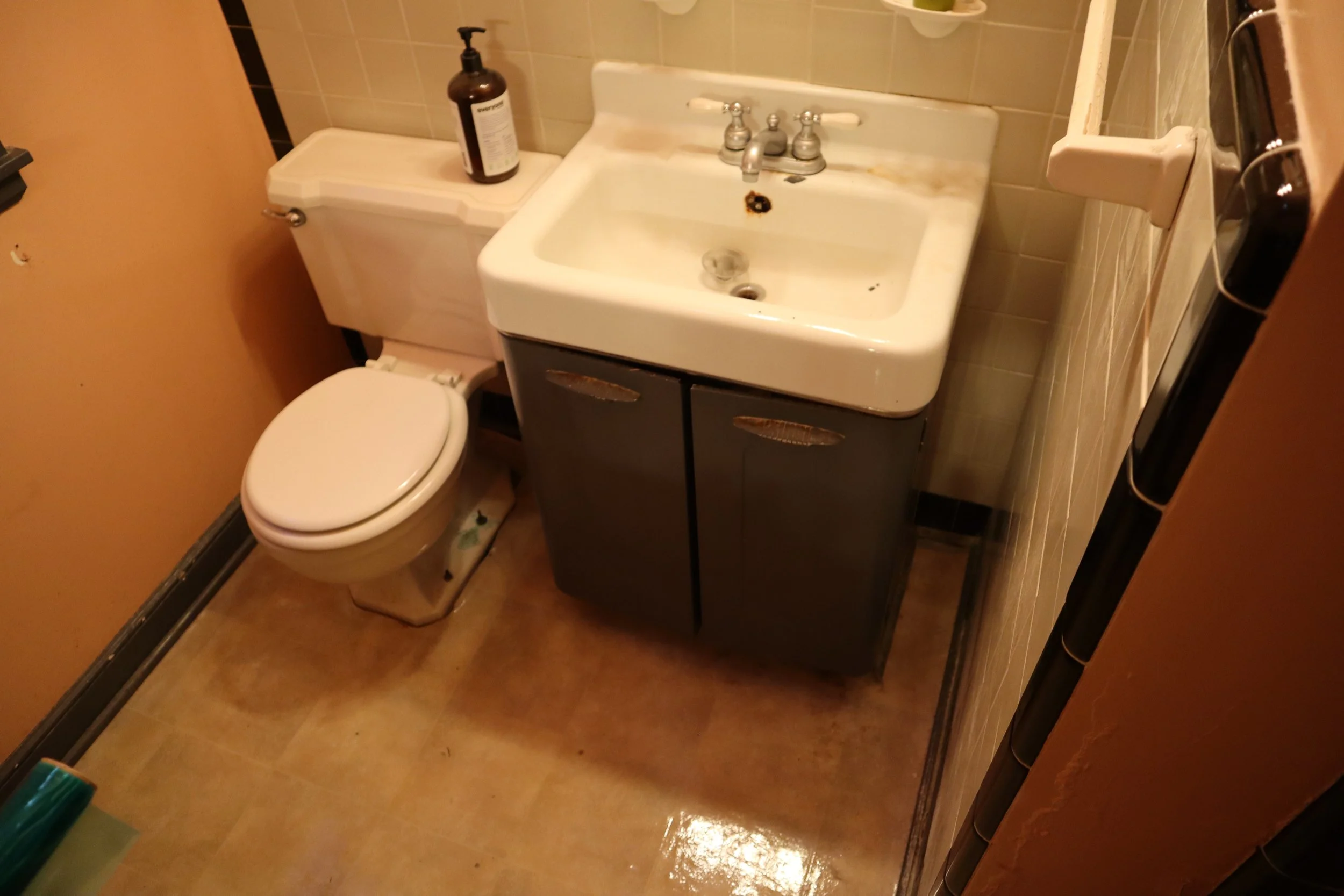 Before: 1980's style vanity and toilet. 1950's wall tile