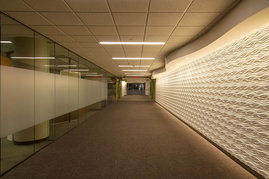 This is the main entry corridor on Level 3 from the main staff parking garage. The generous width of 14’ allowed accenting the length with new textured wall panels, the wave header and specialty lighting.