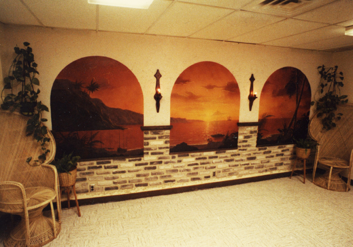 In 1977 after graduating high school and prior to working as an architectural/interior designer Brad worked for a short time at a local Target store in maintenance department. Brad couldn't stand all the bland walls in the break room nor could the other employees, so Brad whipped out this mural painting a tropical sunset scene requisitioning paint department and some fake "Z" brick, chairs and plants from the Home & Garden department.