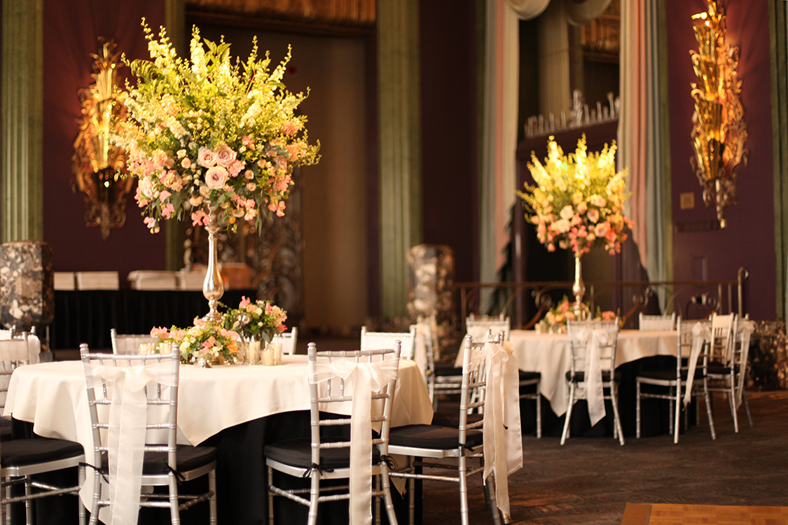 Elevated garden centerpieces in the Continental Room at the Hilton Netherland Plaza Hotel, by Cincinnati wedding florist Floral Verde LLC. Centerpieces contains coral sweet peas, apple blossom yarrow, Ambridge garden roses, Chablis spray roses, apricot stock, Quicksand roses, White Majolica spray roses, white larkspur, baptisa, Bailey's compact viburnum, bupleurum, gunnii eucalyptus and seeded eucalyptus.