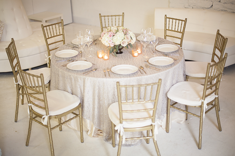 Low centerpiece in a metal compote with blush spray roses, apricot stock, Quicksand roses, white hydrangea and seeded eucalyptus, by Cincinnati wedding florist Floral Verde LLC.