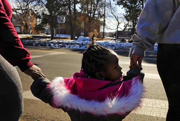 Taleah Howard, left, holds her daughters hand, Tami'Jaye Howard , 2, along with family friend Jazmine Lockett as they cross the street to their apartment Thursday in Montbello. Members of the Montbello community launches talks about reducing violence in the neighborhood. (RJ Sangosti, The Denver Post)
