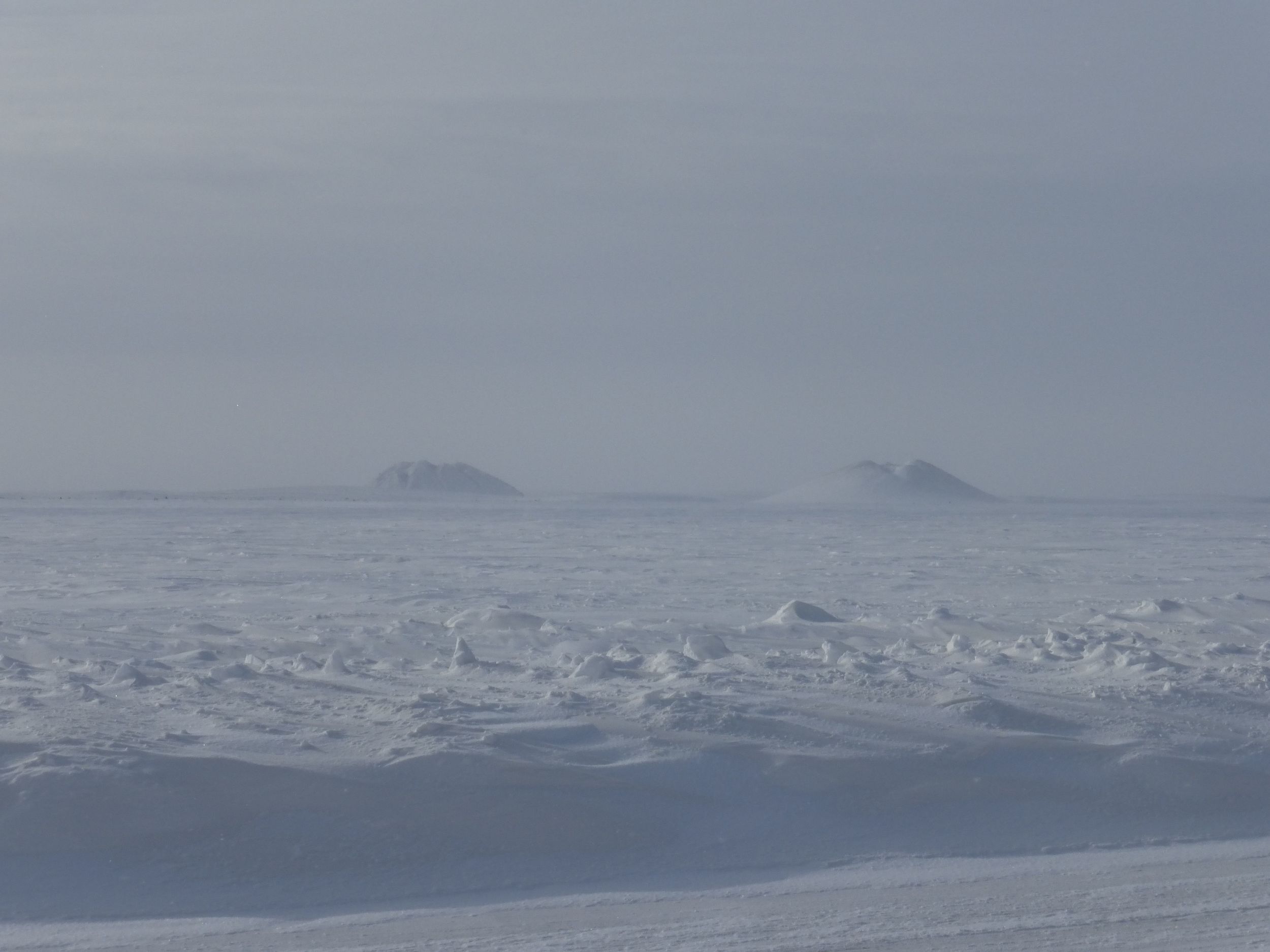 I get a glimpse of Tuk's Pingos, they are formed when water goes through the soil and then freezes underneath.