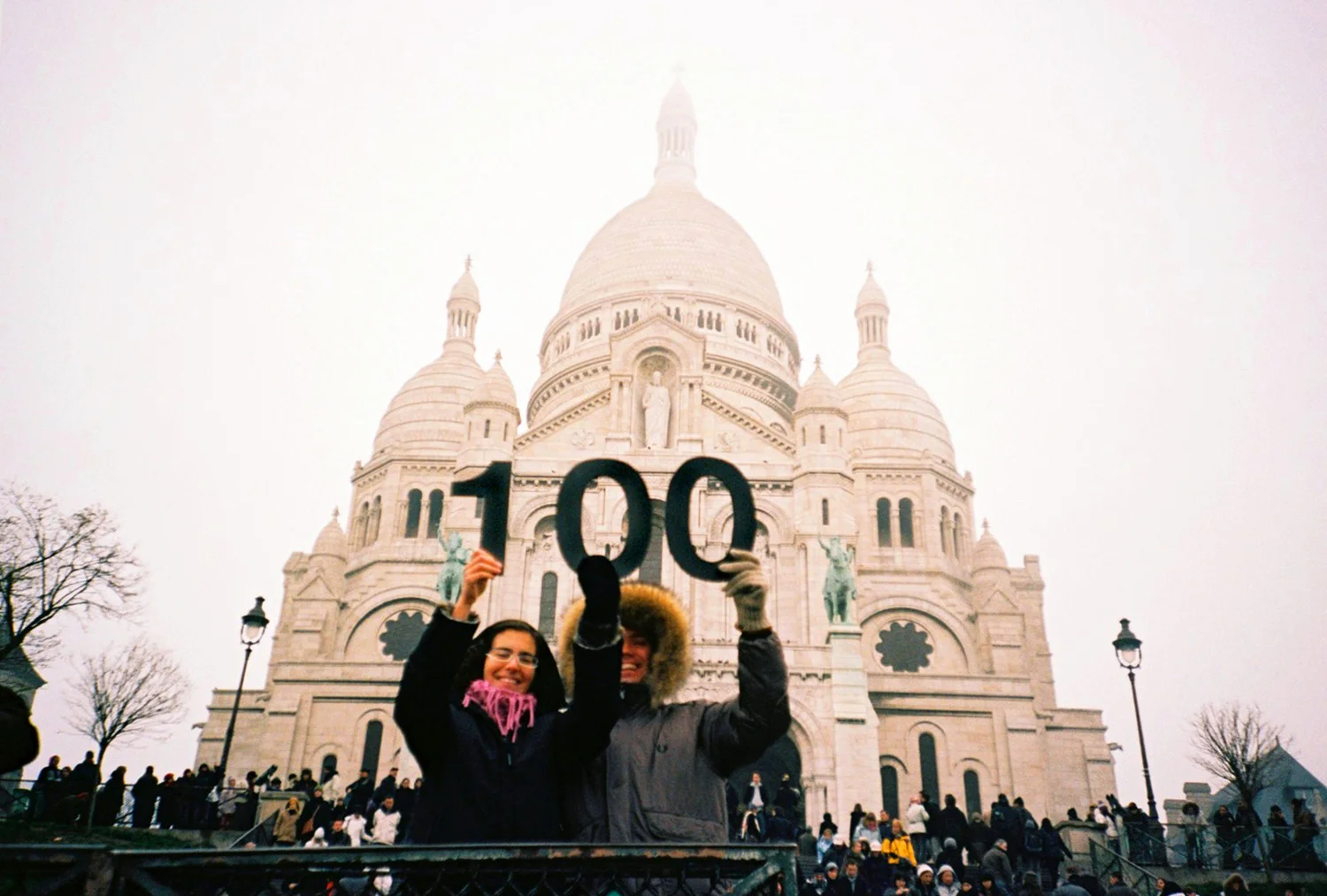 The main idea of the 100th film taken in Paris is capturing local people holding the big figures of '100' with iconic architectures of the city.