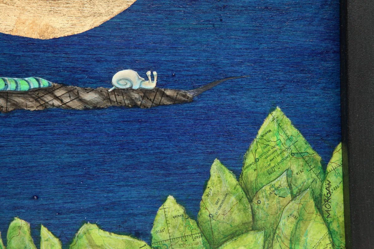 A large golden moon glows in a deep blue sky. Two snails and a green caterpillar rest on a branch above sheet music patterned leaves. Peaceful, whimsical scene using vintage maps layered with ink wash
