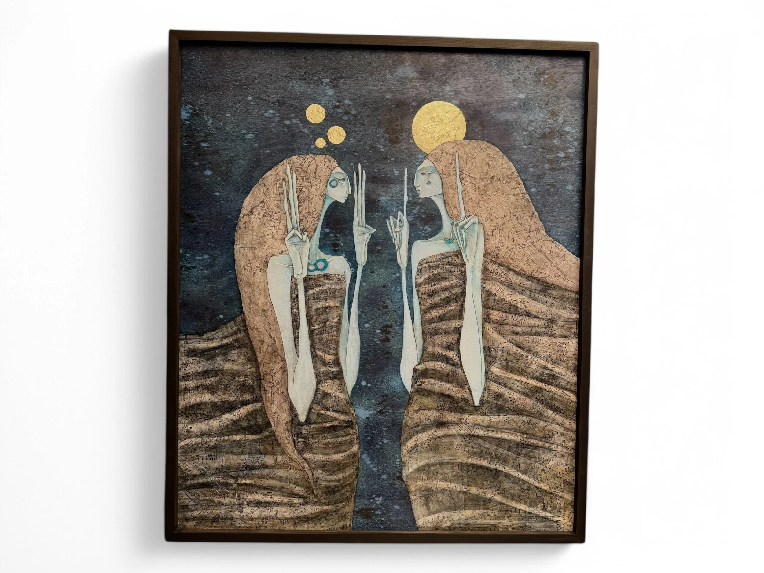 Two tall, slender, blue-skinned figures wrapped in earth-toned cloaks face each other against a dark blue, starry background. Features collaged sheet music & maps layered with ink wash and gold leaf