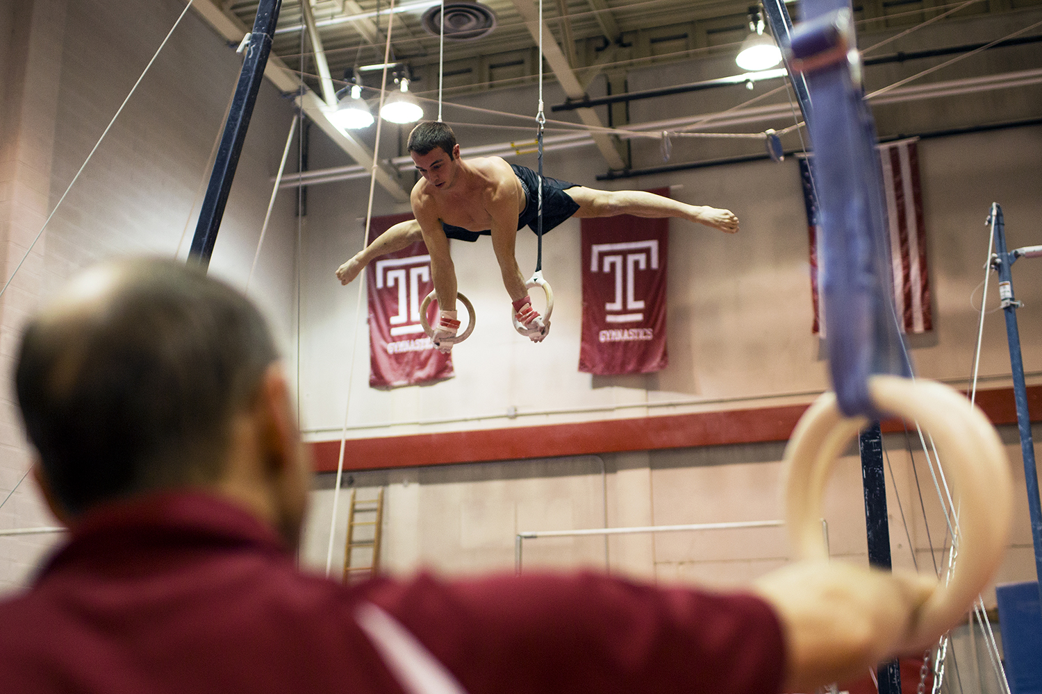 Longtime men's gymnastics coach Fred Turoff watches sophomore Casey Polizzotto practice on the rings in McGonigle Hall on Jan. 26.