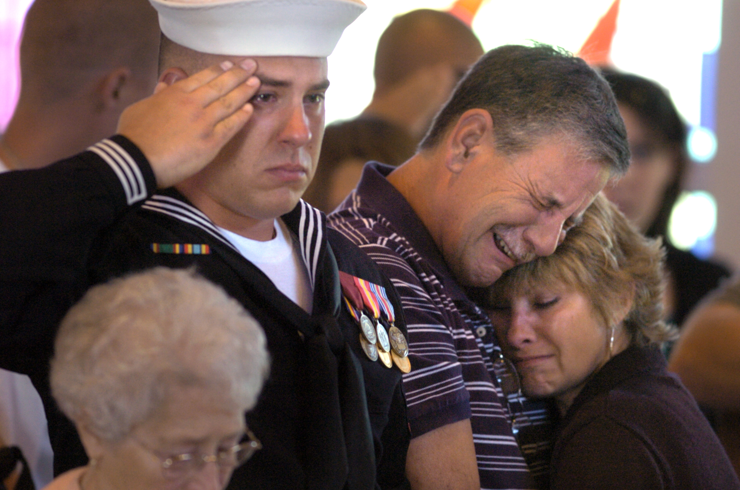 Justin Hall salutes, and parents Kevin and Becky Hall embrace during a memorial service for their brother and son Marine Corps Veteran Eric Hall at Faith Lutheran Church in Punta Gorda, Fla. The missing Marine's body was found in a remote area of Deep Creek after post traumatic stress disorder from the Iraq War caused him to flee a relative's home.