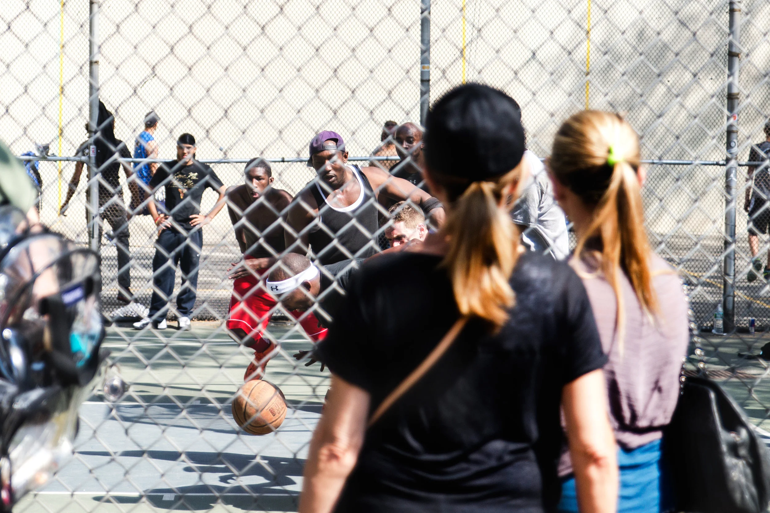 Guys playing a pick-up basketball game with spectators watching.