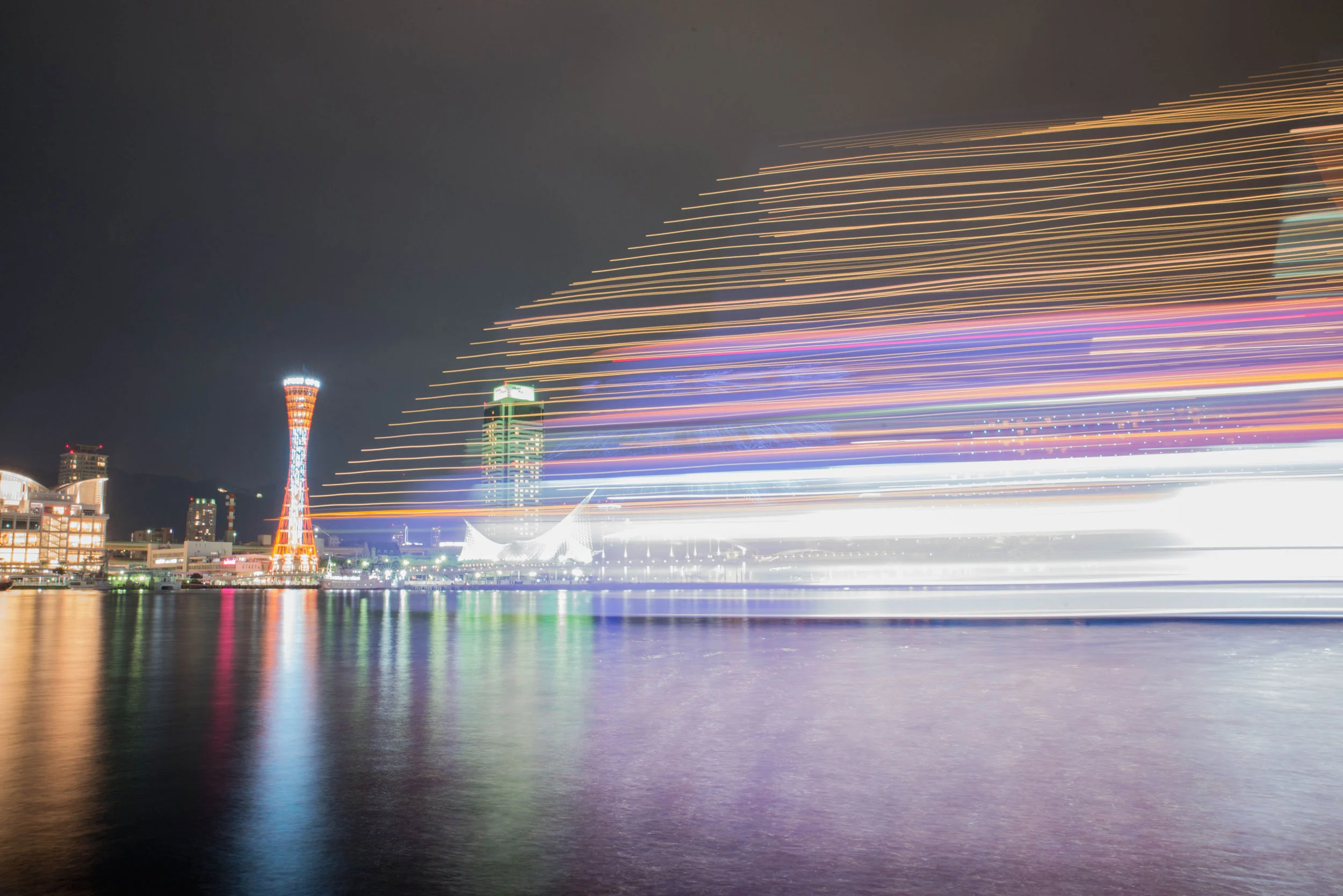 A passing boat creates light trails at the Port of Kobe