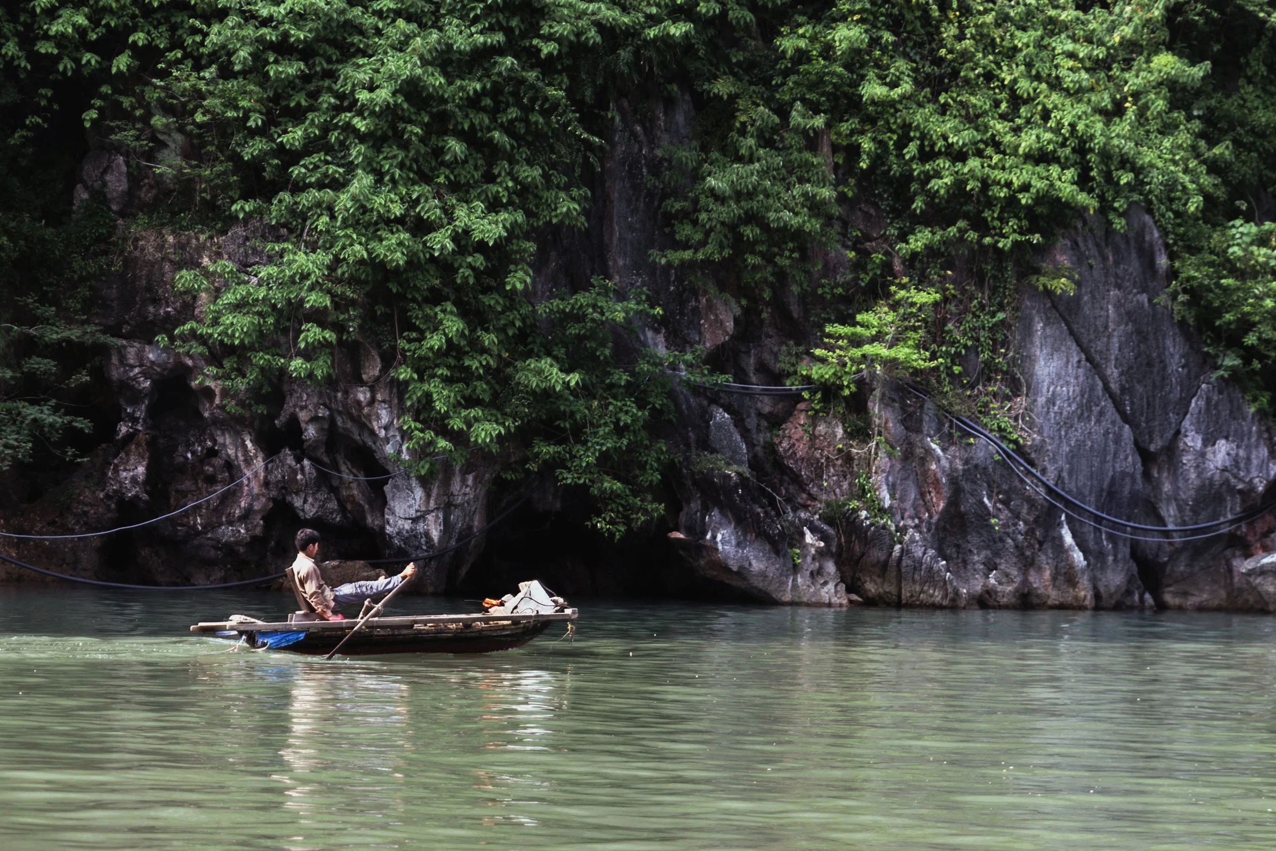 Vietnamese man rowing a boat with his feet in Ha Long Bay