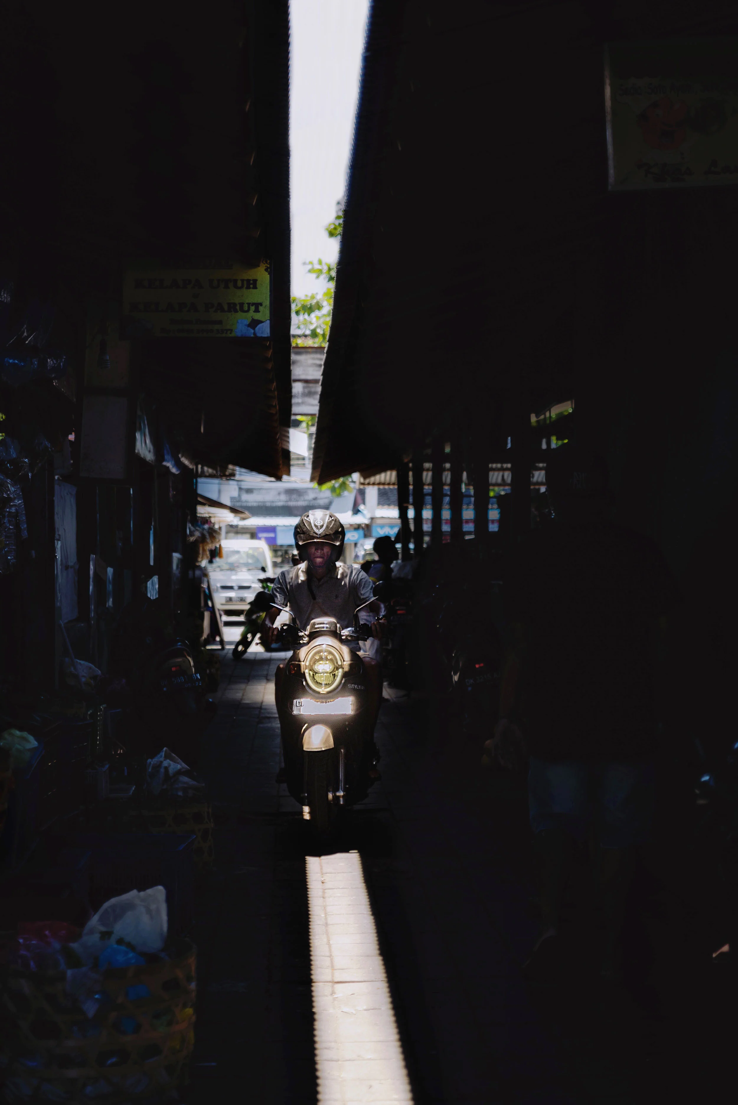 A moped drives through Pasar Taman Sari market