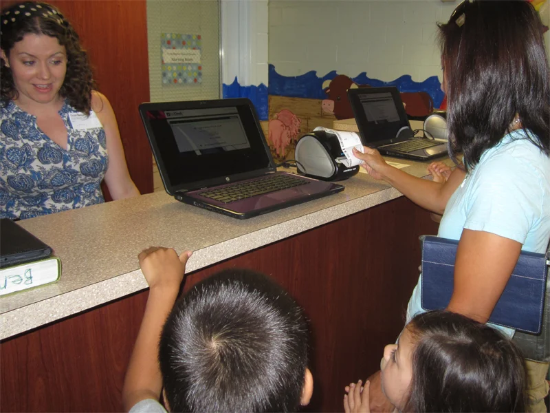 Mom checks in with ACS at the preschool check-in desk.
