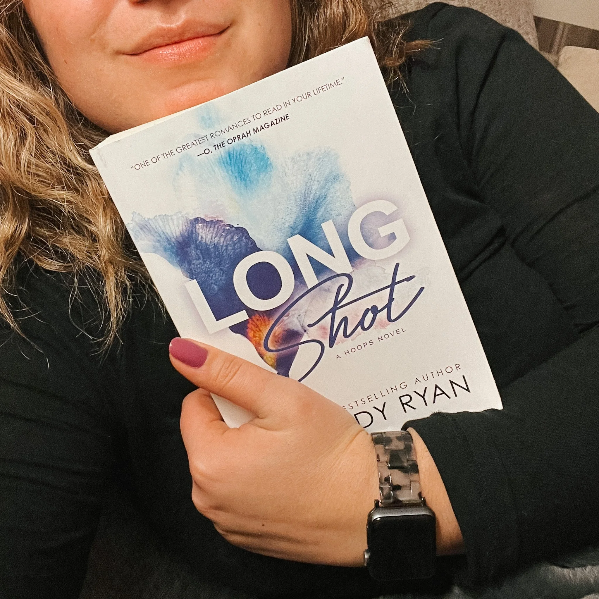 a white woman with a soft smile hugging the book "long shot" in front of her chest
