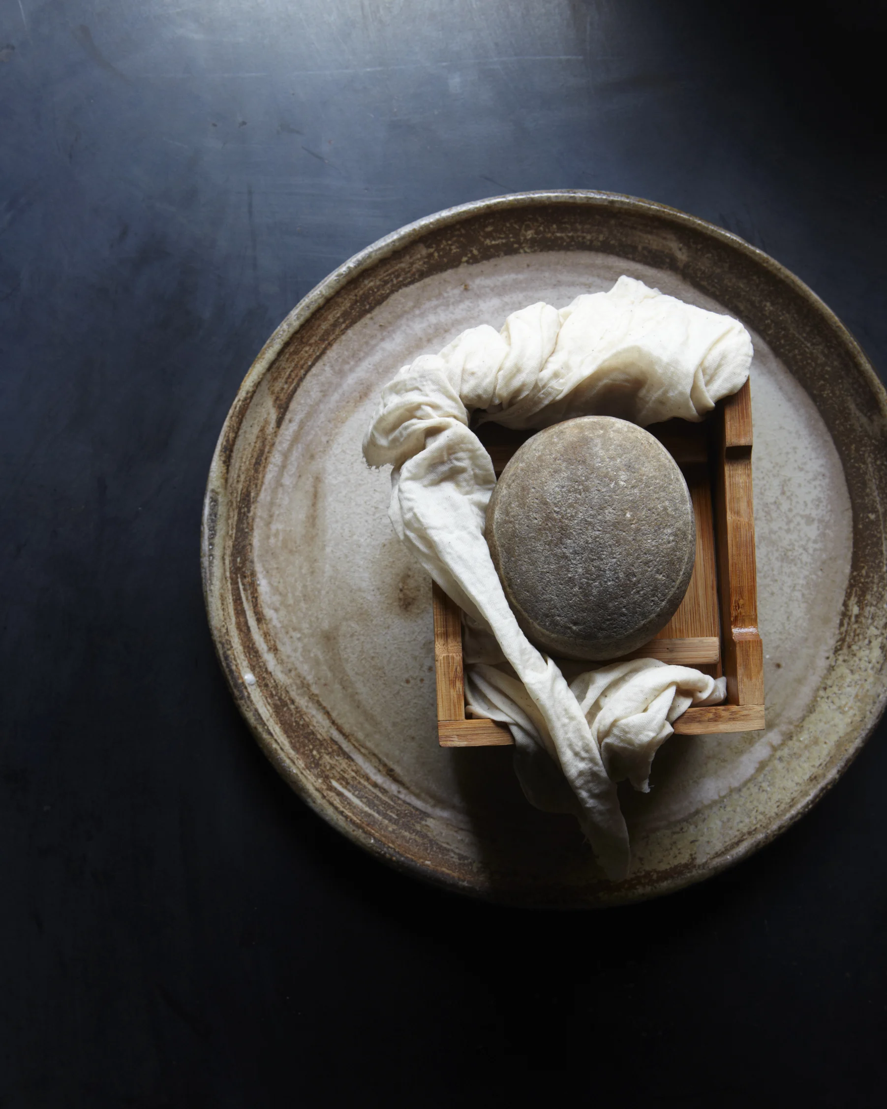 pour the soy milk into the mold over the sink. once most of the excess liquid has drained, place a weight on the mold to press remaining liquids