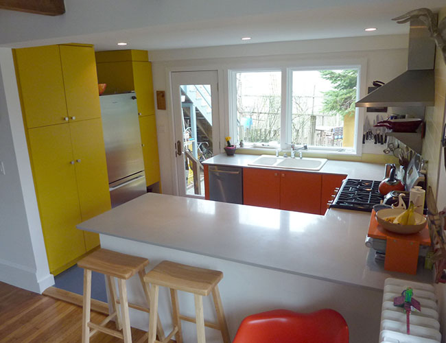 Cabinets in bright custom colors complement neutrals on walls and countertop.