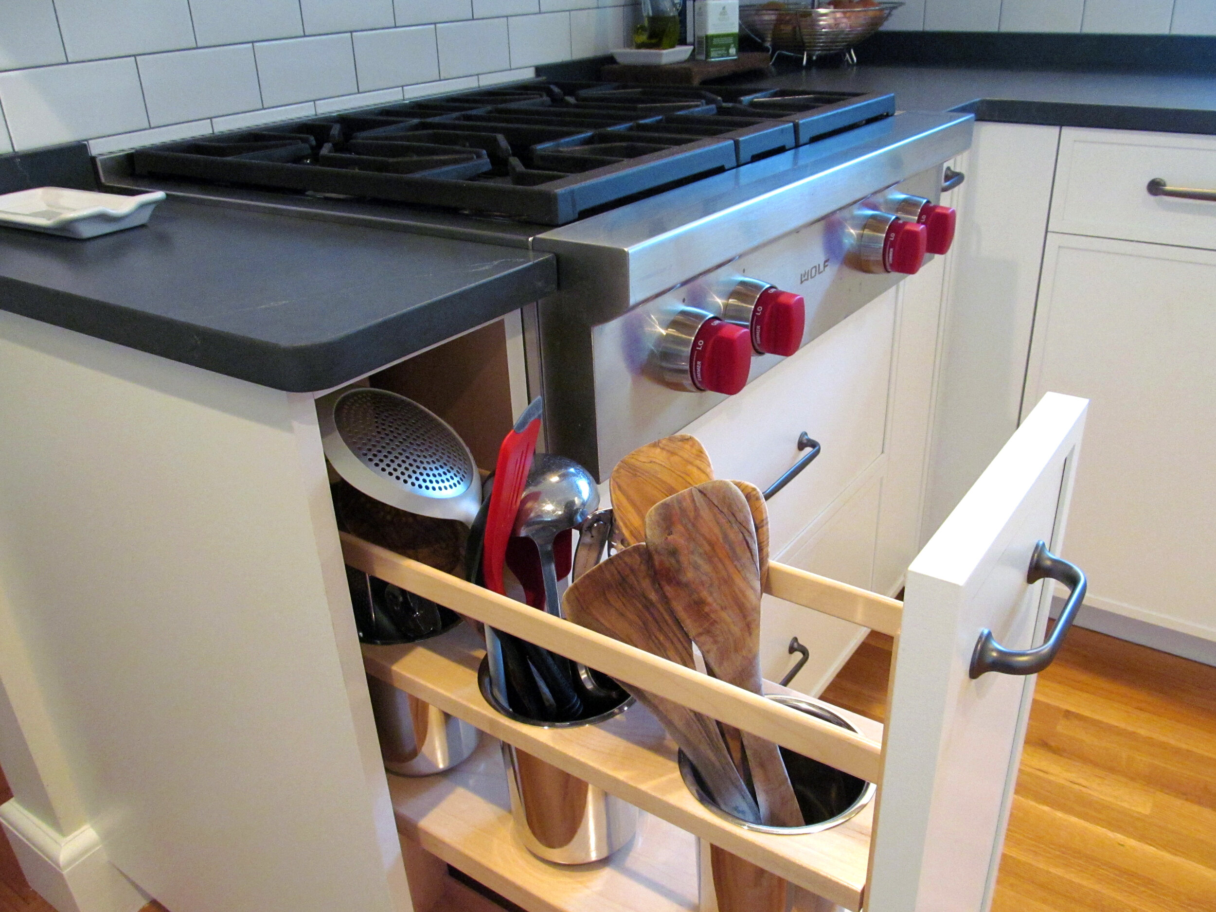 Stainless steel canister base pullout next to the range keeps utensils close at hand.