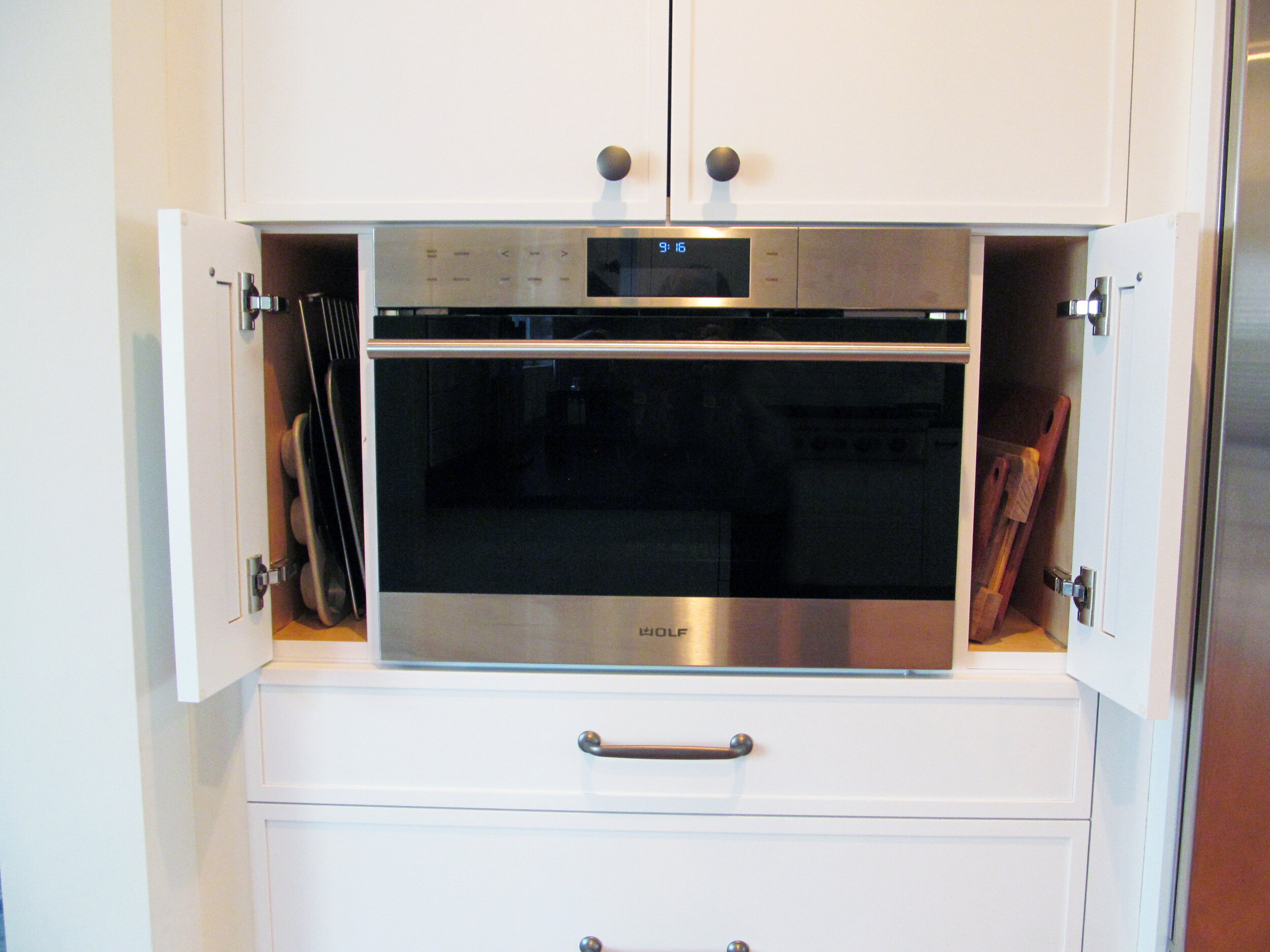 Vertical storage on both sides of the built-in microwave are handy for cutting boards and other flat objects.