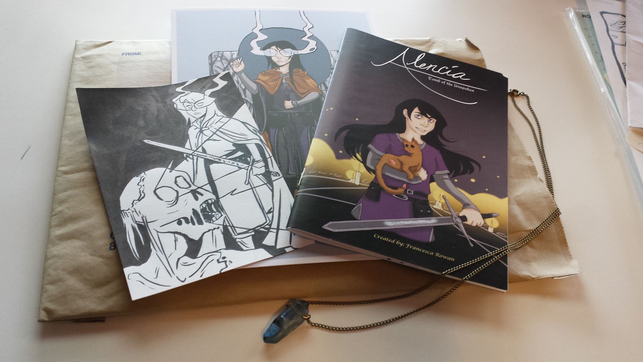 "Adventure's Pack" featuring a copy of "Alencia: Tomb of the Unspoken," a 6x9" Alencia print, an original Alencia ink drawing that appeared in the first Alencia book, and a raw crystal necklace made by myself.