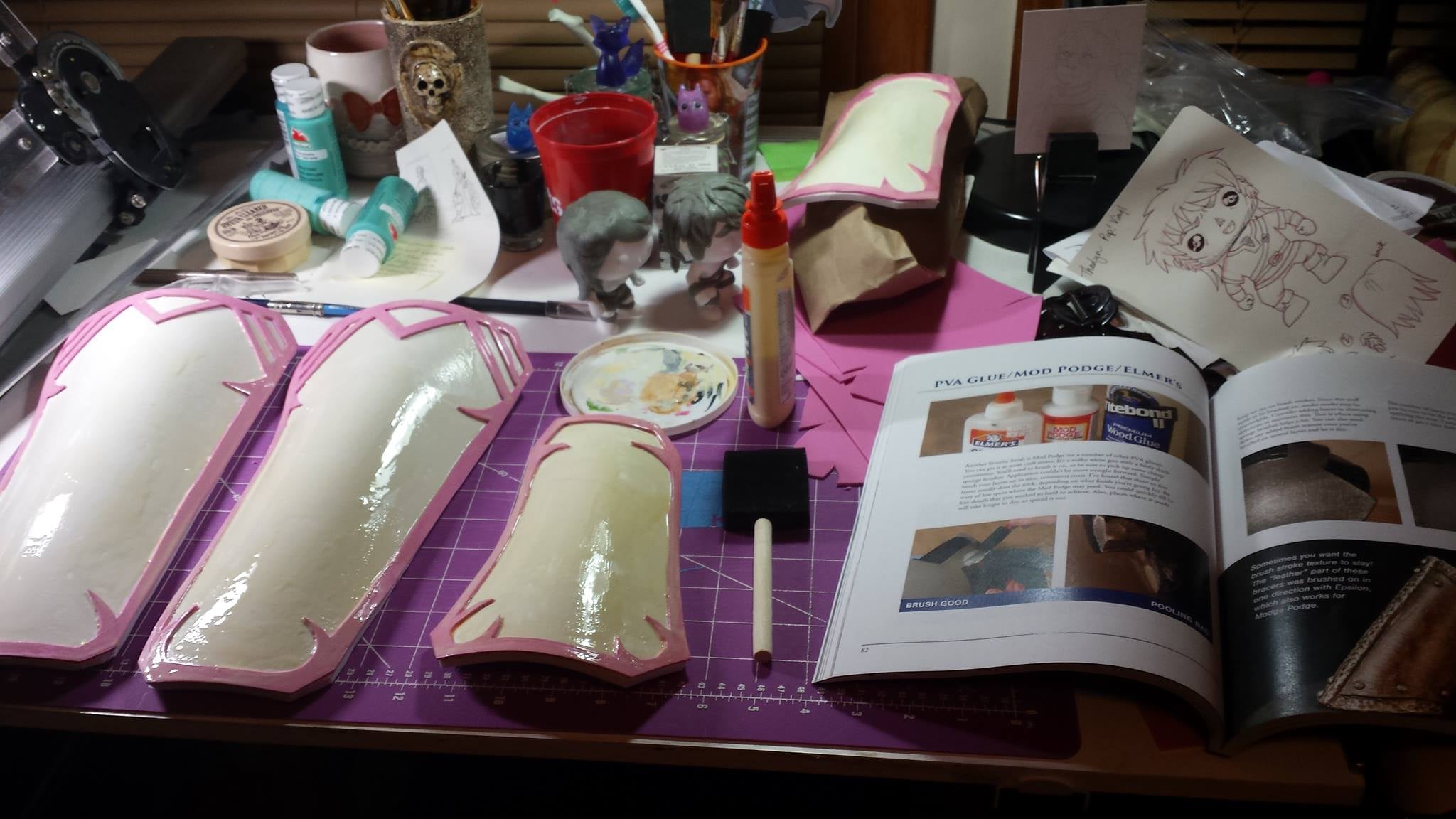 My desk after applying wood glue to the bent pieces of foam. The book I'm using as a guide is "Foamsmith" by Bill Doran. Check out his YouTube channels for more tutorials!