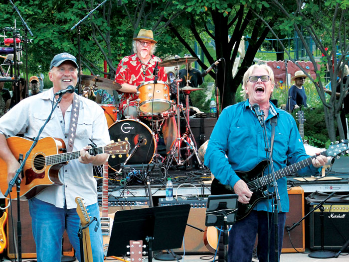  Kevin Odegard, right, sings and mans an electric guitar as Jeff Dayton, left, plays the acoustic guitar and Scott Sansby plays the drums during the annual “Salute to the Music of Bob Dylan” Aug. 1 at Veterans’ Memorial Amphitheater in St. Louis Park