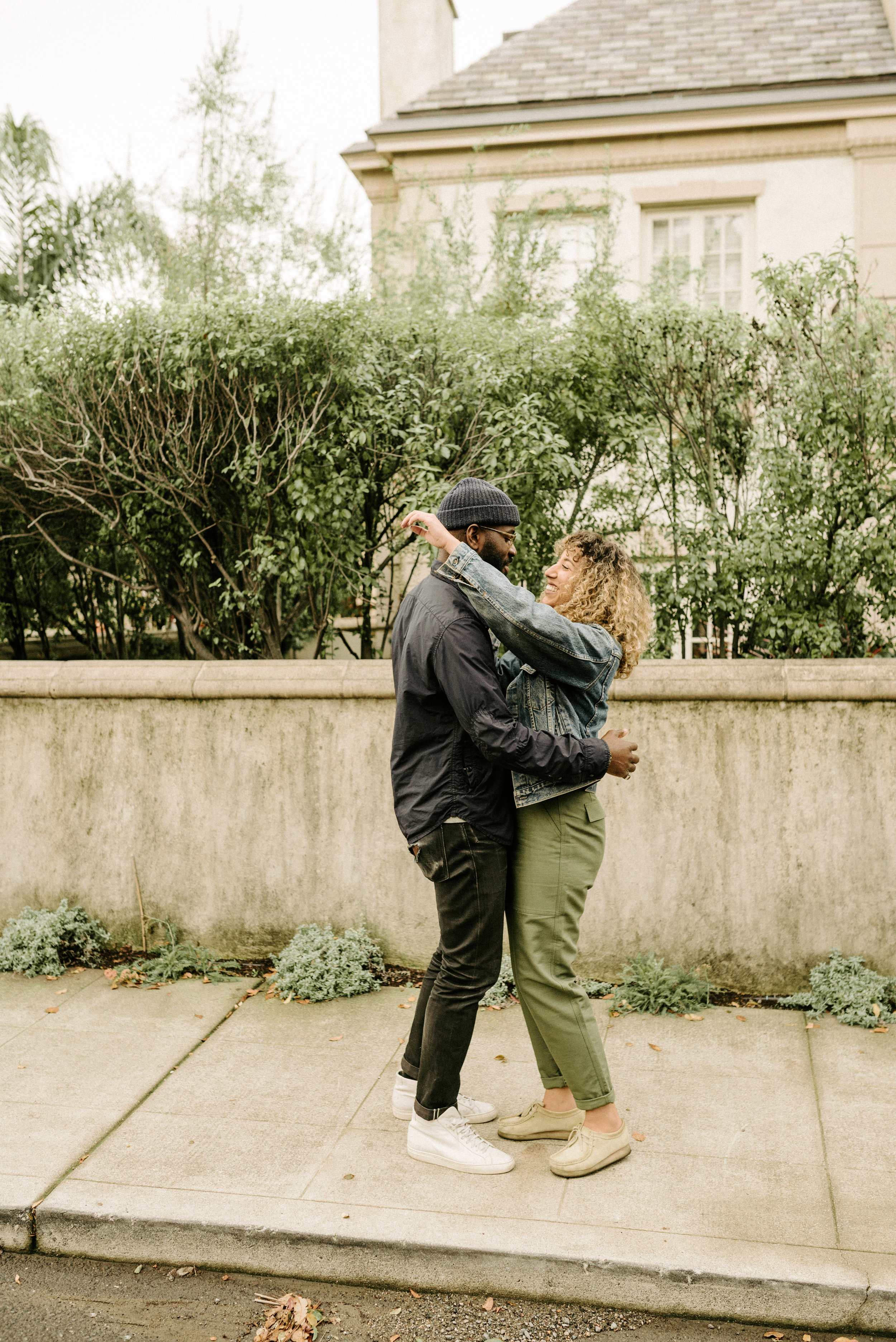 couple hugging on the sidewalk in upper rockridge. photo by oakland wedding photographer