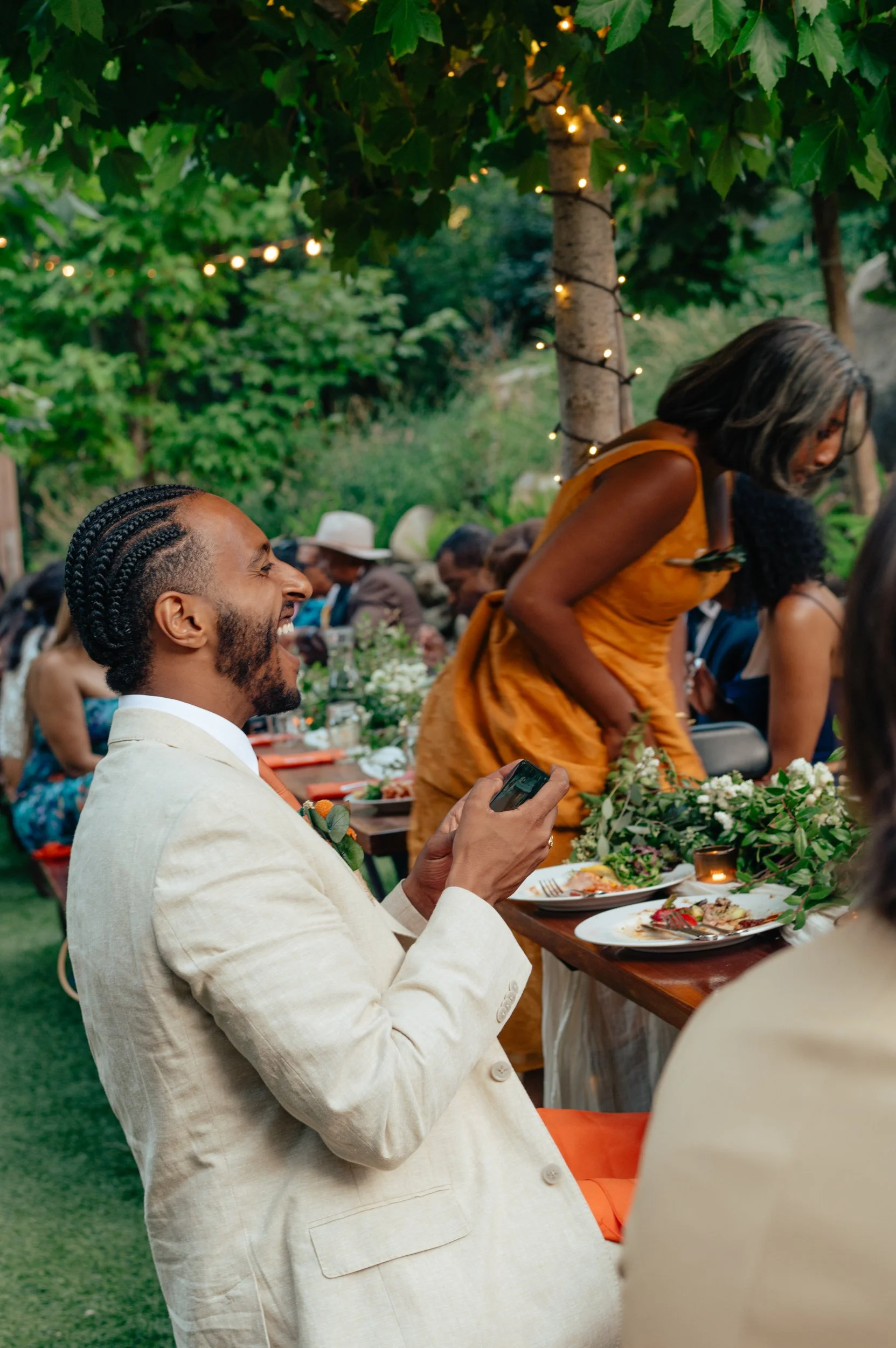Guest laughing at long dining table at an intimate wedding reception dinner, photographed by Amira Maxwell