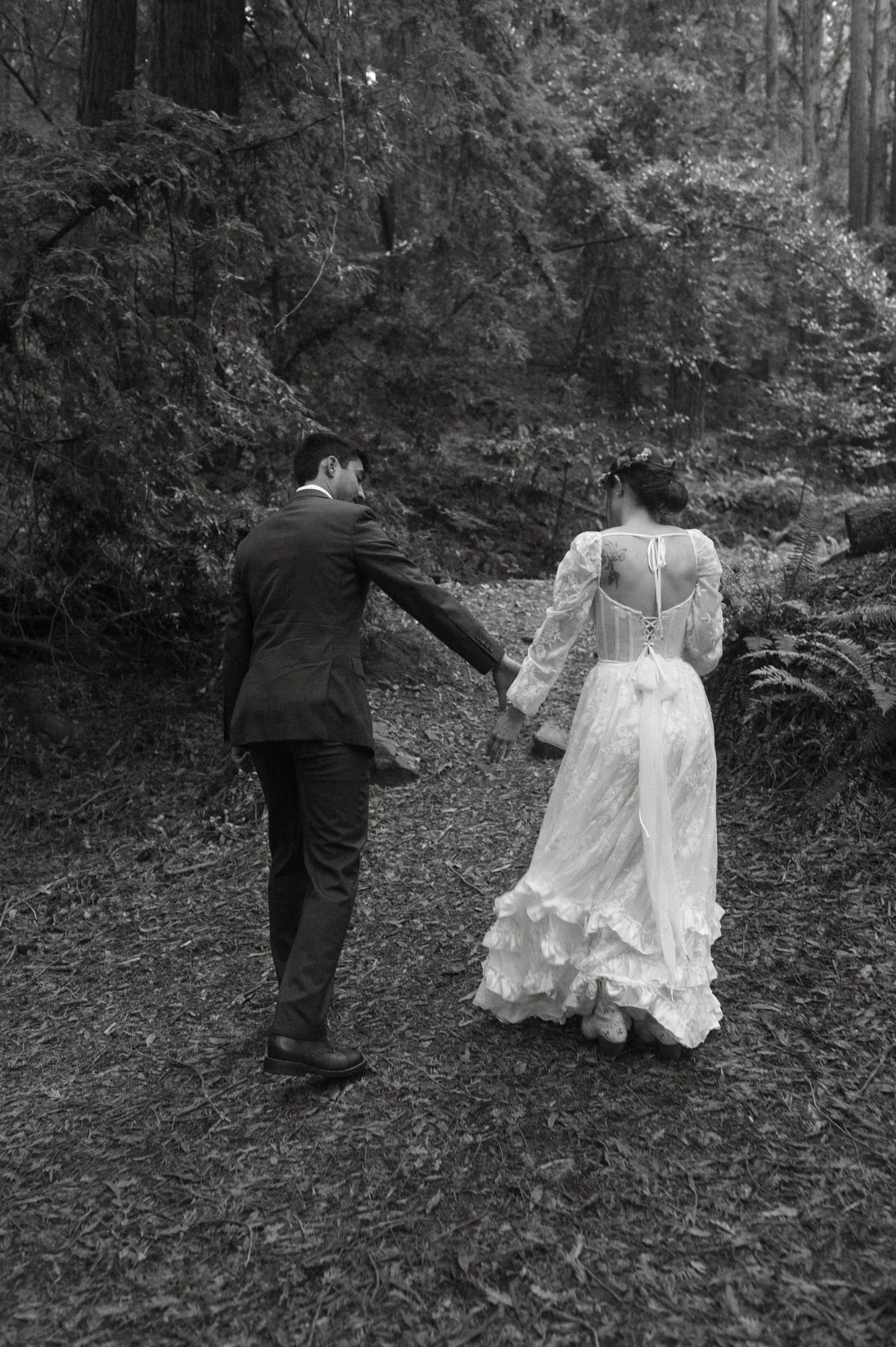 Couple walking into the redwoods before their Oakland wedding ceremony.