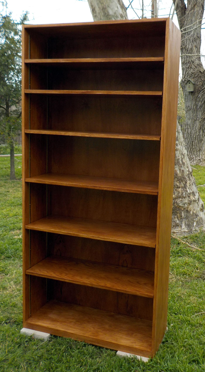Super sturdy bookshelf made of red oak plywood, hand banded with red oak banding, stained with antique walnut, and brass shelf standards.