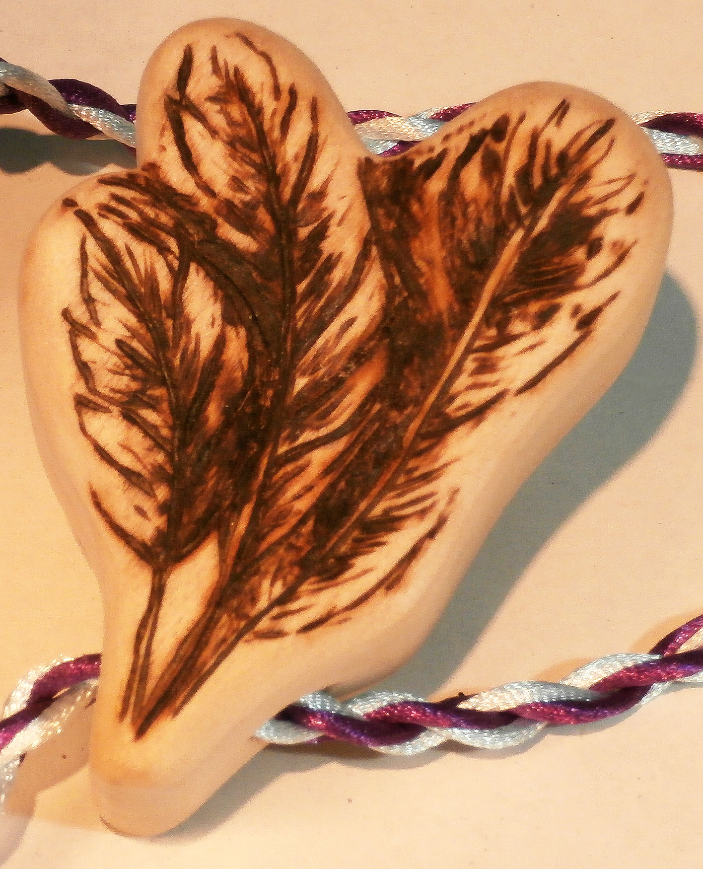 Wood burnt detail of feathers on teether handle for baby shower gift. 