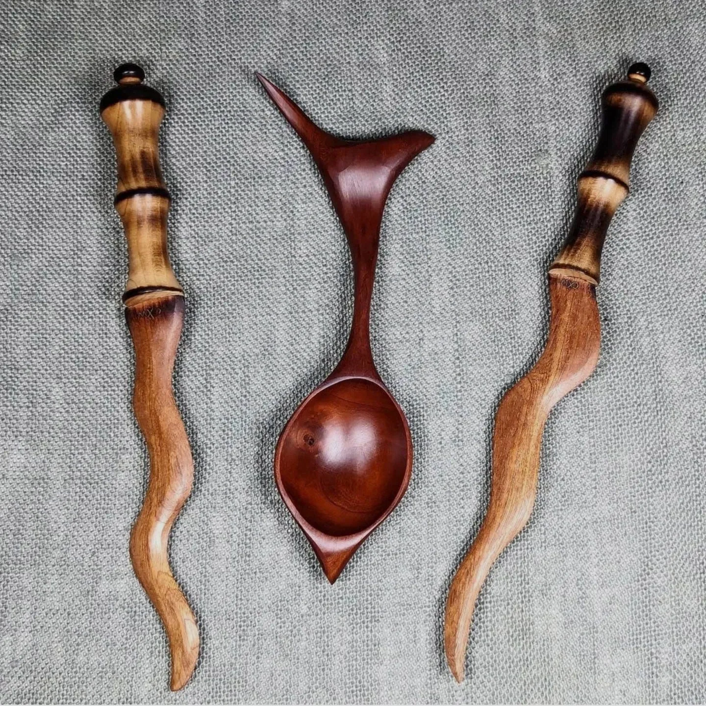 Two hand carved wood athema knives with curvy blades and a whimsical black cherry wood spoon. made by Chaos Woods.