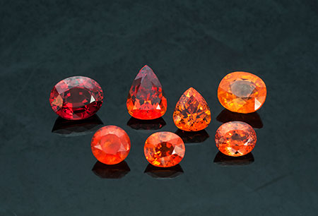 Spessartite Suite: (l–r from top row) 24.80-carat oval from Nigeria (Inv. #13832 ), 17.71-carat pear shape from Nigeria ( #20423 ), 12.90-carat pear shape from Nigeria ( #16043 ), 22.73-carat cushion from Tanzania ( #21599 ), 12.71-carat round from Namibia ( #1531 ), 10.46-carat oval from Tanzania ( #21598 ), and 11.10-carat oval from Nigeria ( #21569 ). Click to enlarge. (Photo: Mia Dixon)