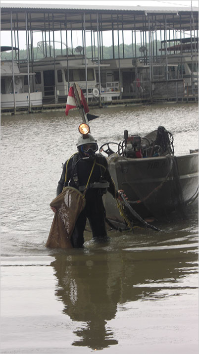Knee deep in the big muddy. A pearl diver. AJA mentions that the danger of such work, together with the lackluster economy in Camden, is a cause for divers being "nearly impossible to find." (Photo: TenneseeRiverPearls.com
