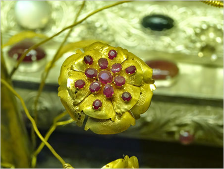 Posy. A jeweled flower composed of gold and rubies. It decorates the base of one of a pair of statues of the Buddha on which devotees apply gold leaf in Mogok's largest pagoda. Not surprisingly, the Buddha images have been removed from the valuable bases, which now are in a vaulted case. (Photo: Eloïse Gaillou © NHMLAC)