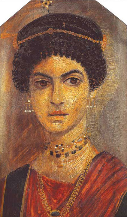 The subject of this mummy portrait (110–120 C.E.) was named "The Jewellery Girl" by Egyptologist Flinders Petrie, who excavated the portrait at the archaeological site of Hawara in Egypt's Fayum Basin, southwest of Cairo (Walker 2000, 52). In her coiffure, the sitter wears a hairpin of pearls and garnets. The topmost necklace matches the hair ornament, but includes other stones that may be aquamarines or sapphires. Below that, a necklace and plaited chain both feature emeralds.