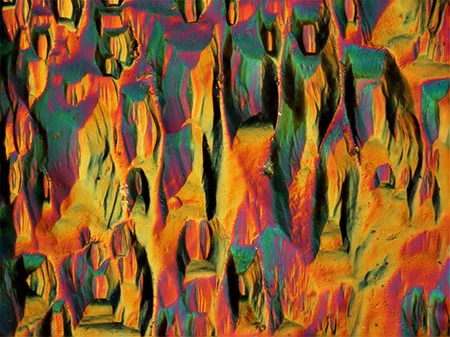 Aquamarine Prism Faces: Using differential interference contrast, the prism faces of an aquamarine crystal show an interesting barrel-shape etch pattern. Photomicrograph by Nathan Renfro; field of view 0.25mm.