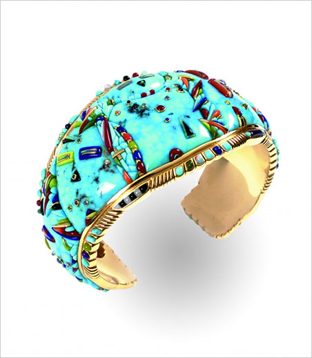 Blessings Bracelet. Raymond C. Yazzie, 2002–2003. Height, 1½ in. Collection of Daniel Hidding. Windsong Studio, L.L.C. In what might be mistaken for a purely abstract design, at least three katsina (aka kachina) forms can be seen in the view above. At left, look for the yellow and blue eyes. Top center, see the black nose topped with tiny green cab; this is the "maiden," with bezel-set cabs portraying nipples and navel of orange and blue, as well as a multi-colored necklace. Overlapping at bottom center—in profile—see the black eye and red nose. (Photo: Gregory R. Lucier)