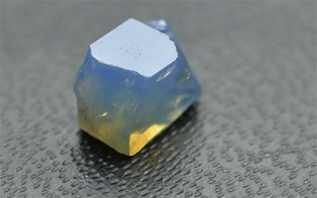 No yellow sapphire samples were amongst those received by the laboratory, but yellow is observed via the Tyndall effect in GIA reference sample 100309934811. The sample was placed on a slightly reflective background and a white "daylight" type fluorescent illumination illuminated it from above. As can be seen, blue color is scattered from the sides of the sample but when light reaches the lower part of the stone it becomes greenish and then yellow as most of the blue is scattered away. (Photo: Vincent Pardieu © GIA)